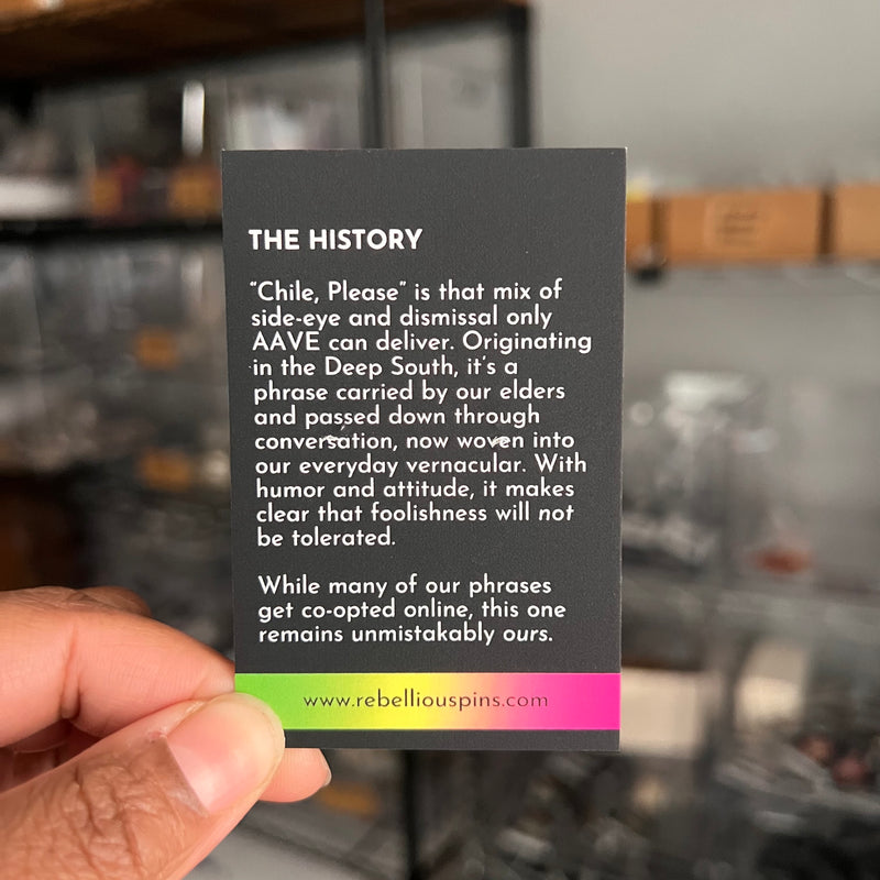 Card with text about 'Chile, Please' phrase held by a hand in a blurred indoor setting.