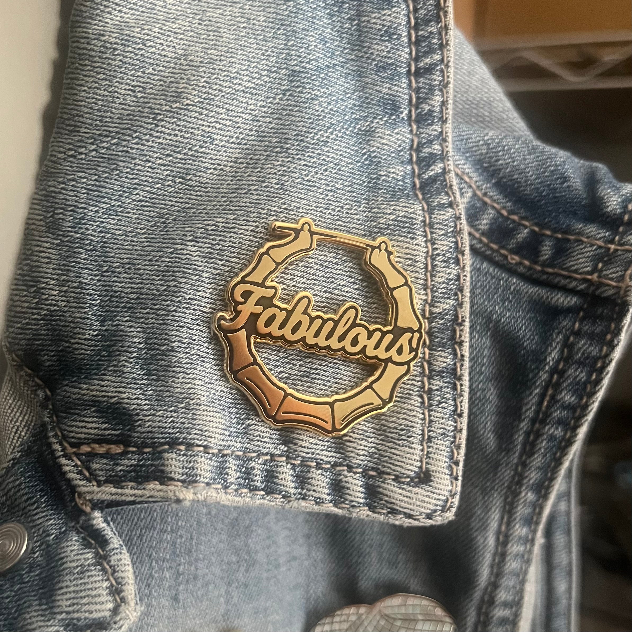 Gold 'Fabulous' pin on a denim jacket