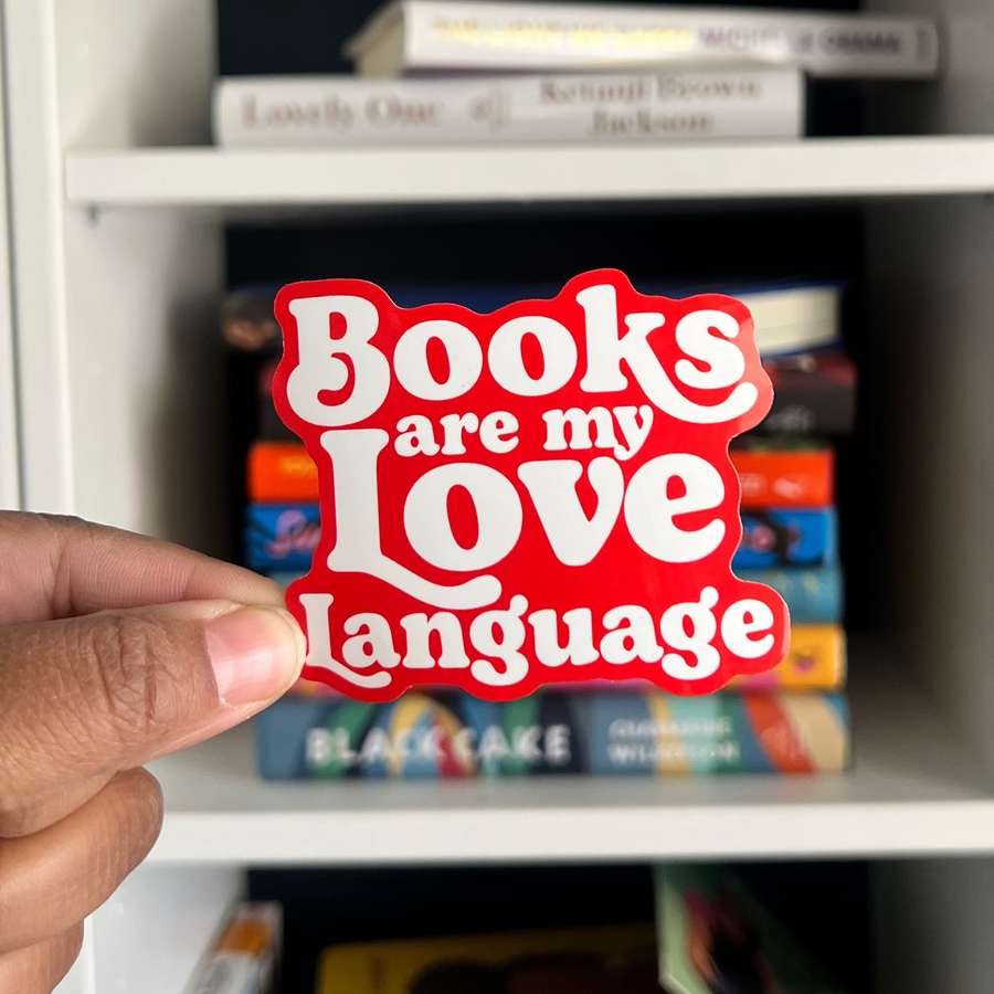 hand holding a sticker in front of a bookcase that says Books are my Love Langauge
