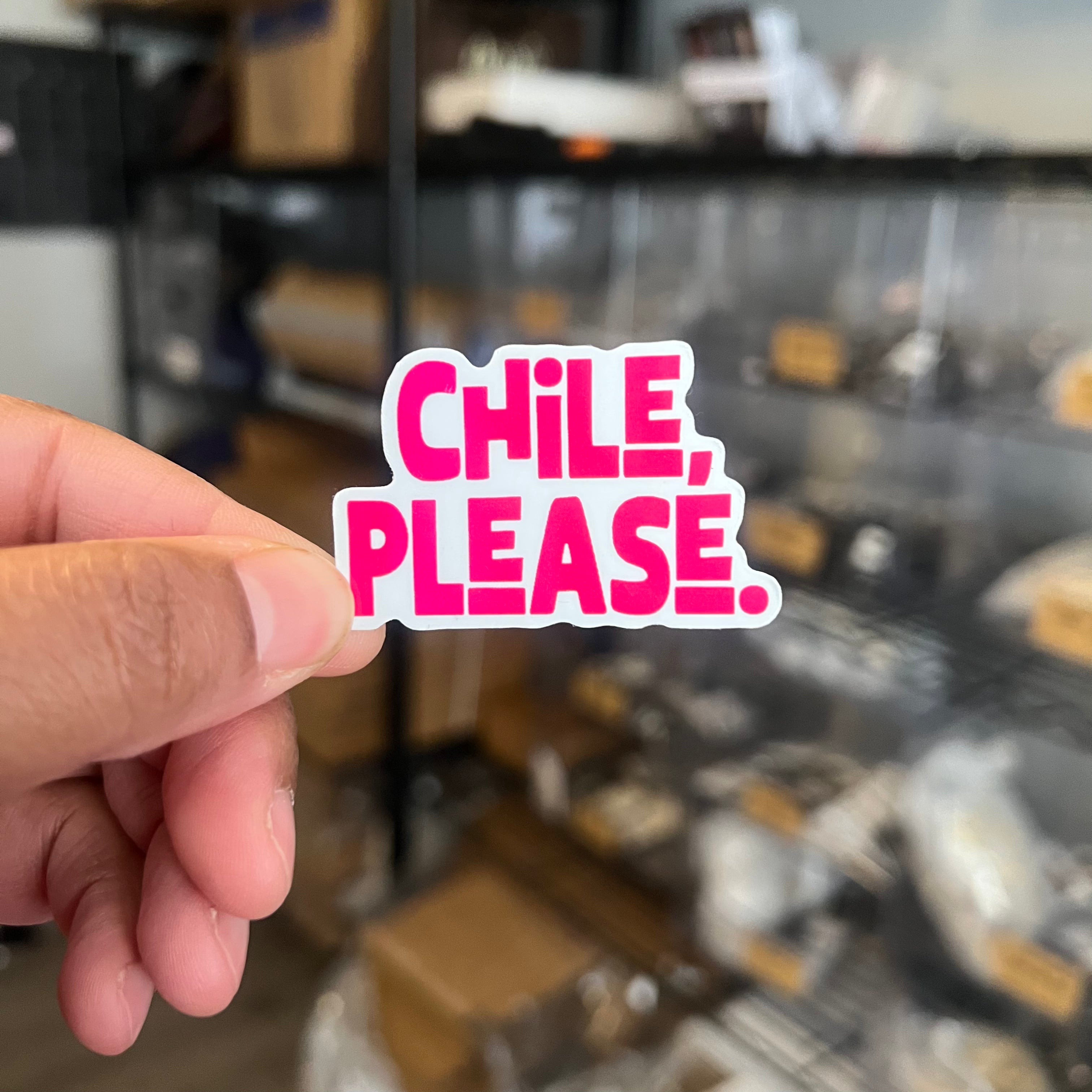 Hand holding a 'Chile, Please' sticker in front of shelves.