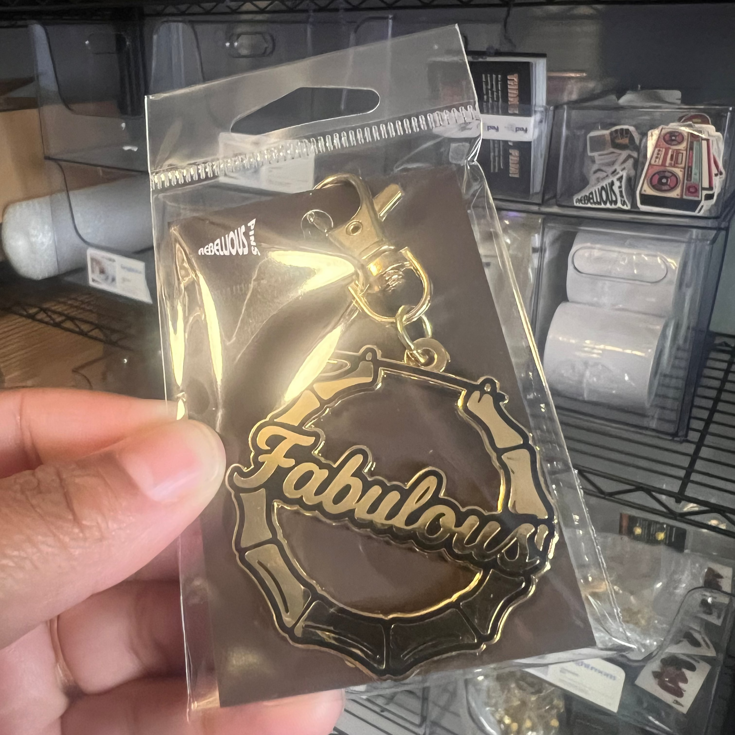 Gold 'Fabulous' badge held in a hand with a store shelf in the background