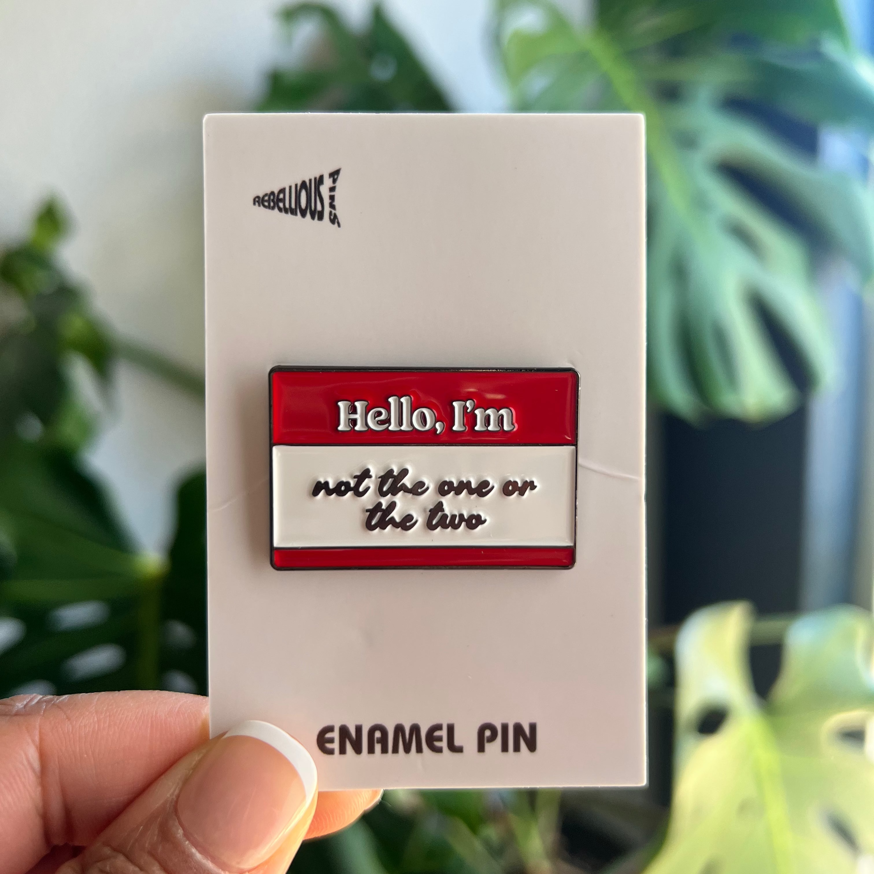 Enamel pin packaging with a plant in the background
