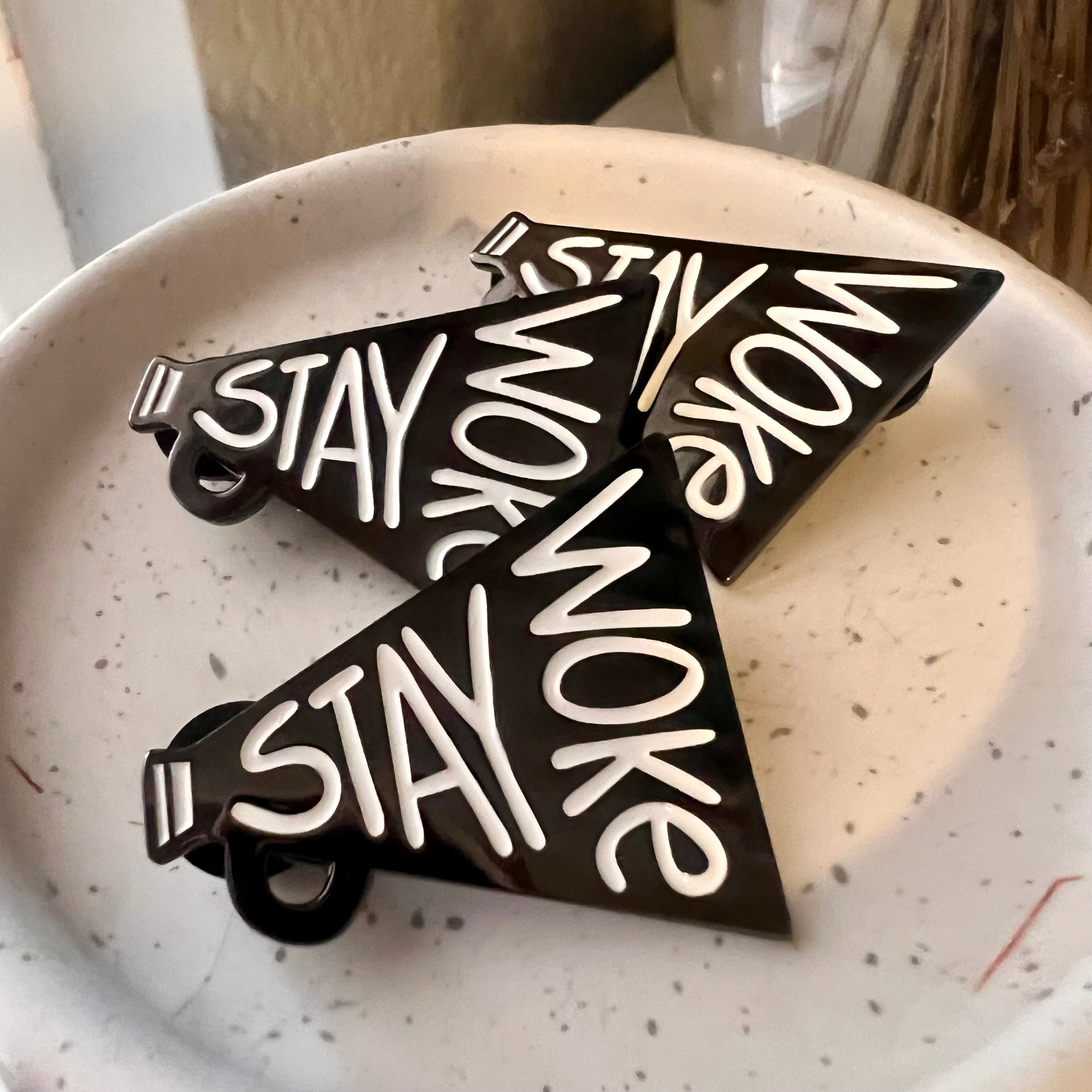 Black and White Stay Woke Enamel Pins on a jewel dish
