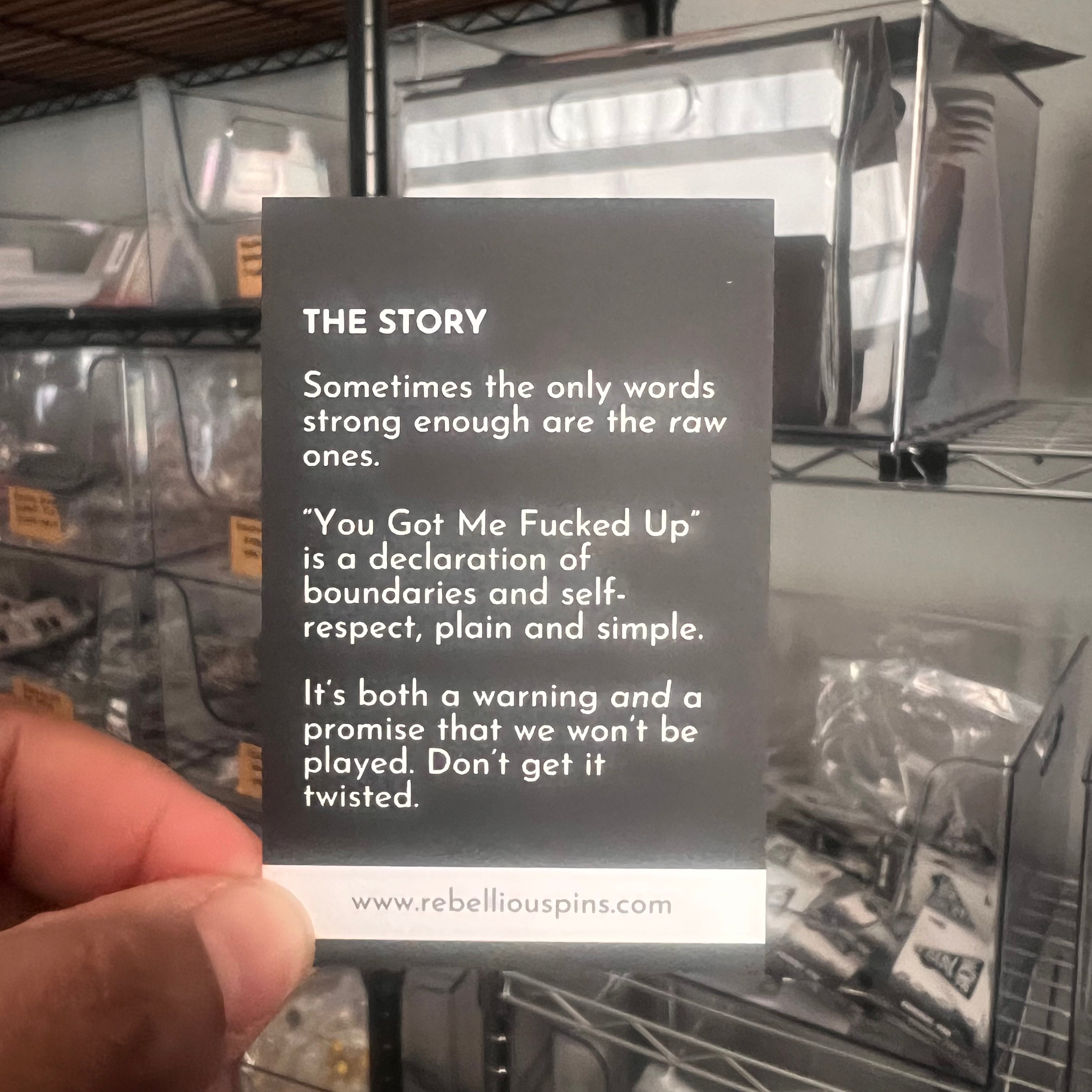 Text card held by a hand with a message about boundaries and self-respect, set against a background of metal shelves.