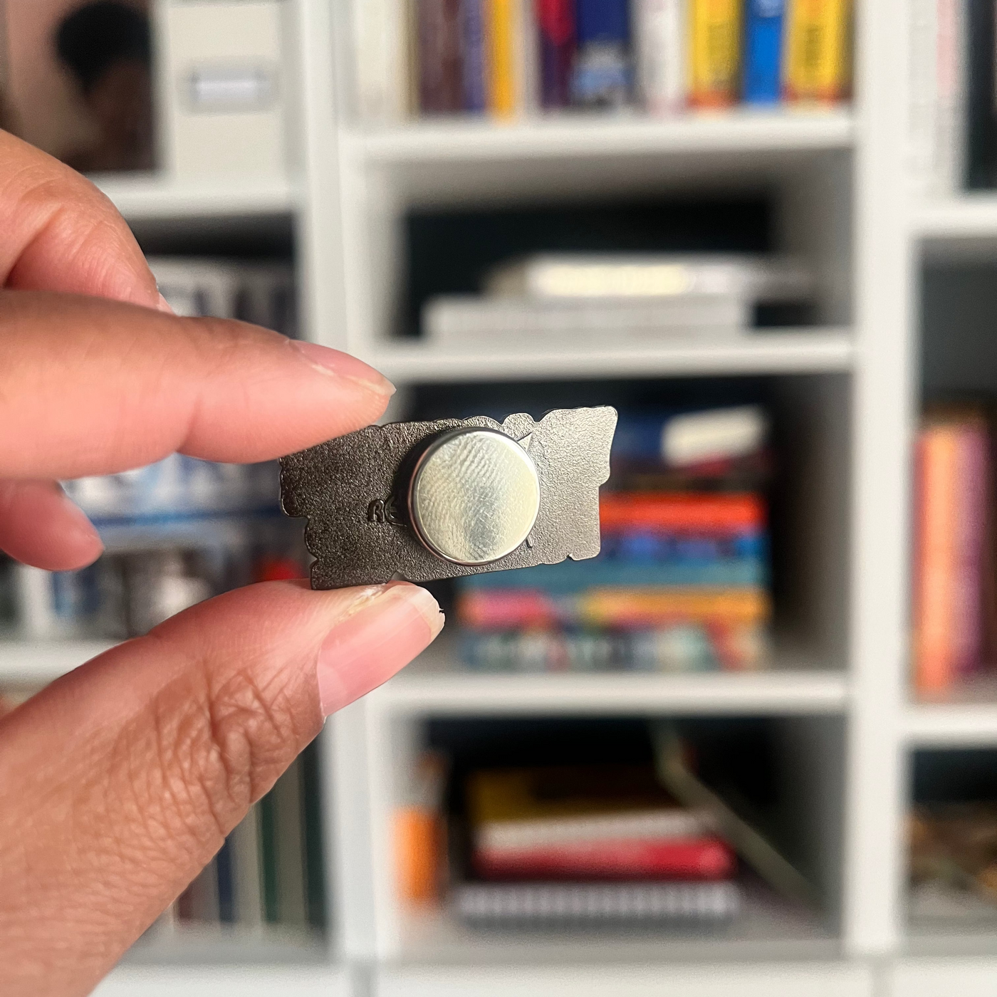 hand holding the You Got Me Fucked Up magnet pin showing the back magnet 