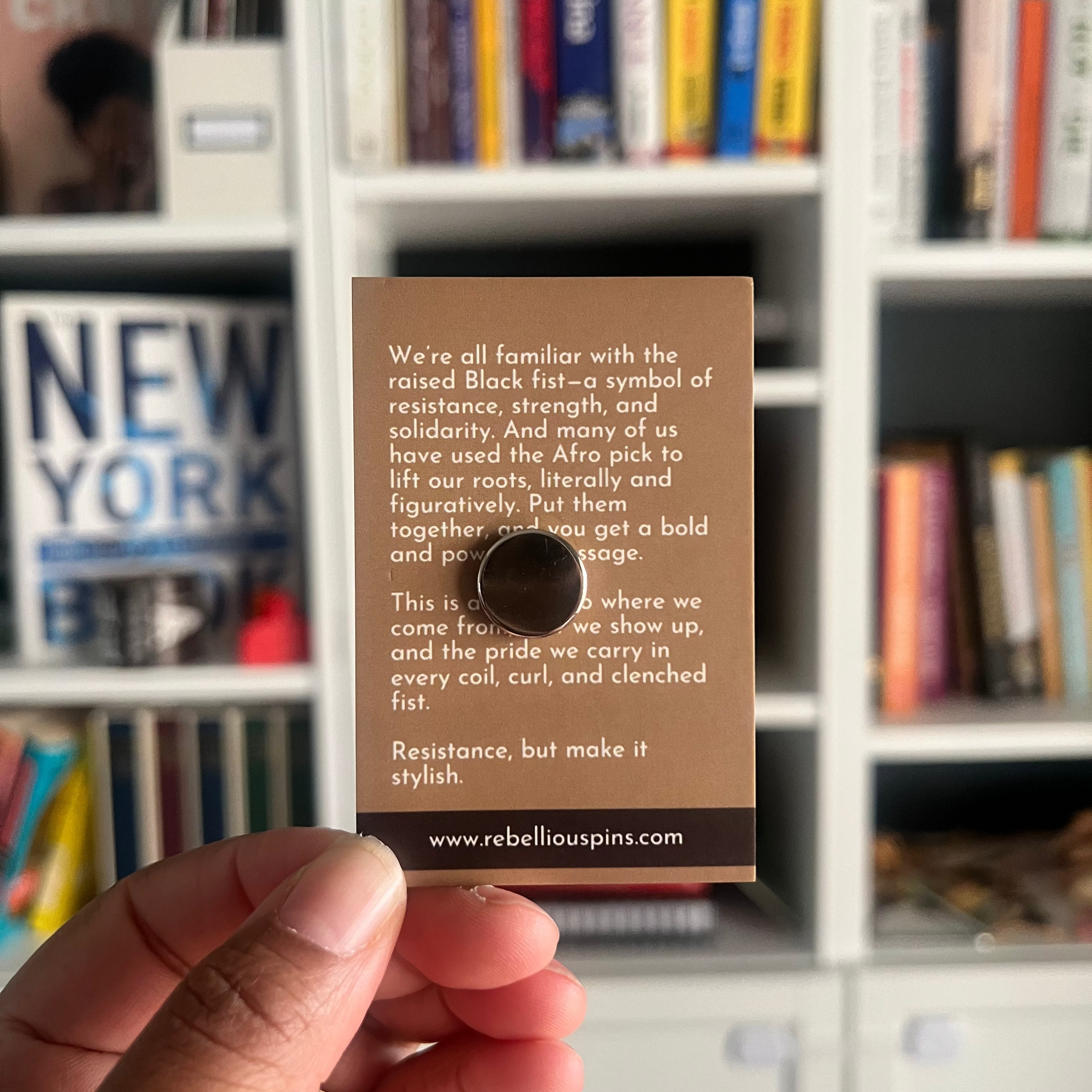 Hand holding a card with text and a magnet in front of a bookshelf